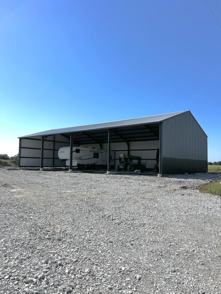 Large open-bay metal barn for equipment and vehicle storage.