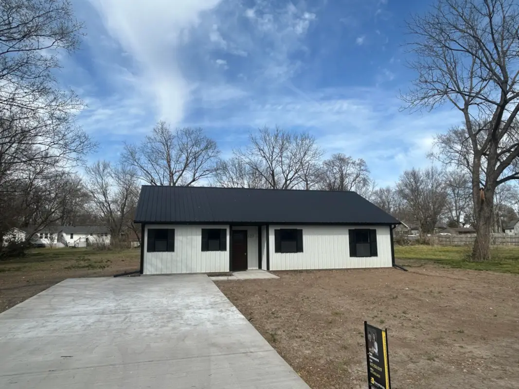 A modern farmhouse with white board-and-batten siding and black metal roof.